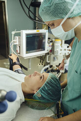 Weibliche OP-Schwester im Gespräch mit dem Patienten auf dem Operationstisch im Operationssaal - MFF002340