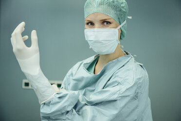 Female surgeon putting on surgical gloves - MFF002346