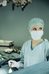Female surgeon holding clamp in operating room during surgery - MFF002354