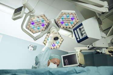 Operating room nurse adjusting operating light during surgery - MFF002362
