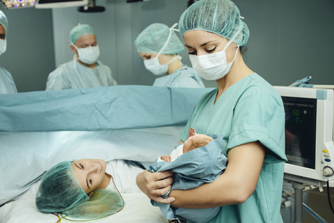 Operating room nurse showing newborn to mother stock photo