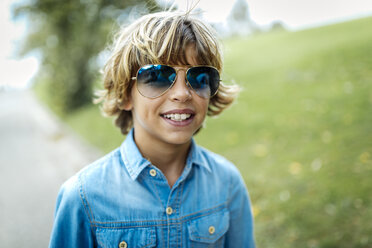 Portrait of blond boy wearing blue coloured sunglasses and denim shirt - MGOF000863