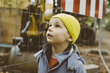 Porträt eines kleinen Jungen mit gelber Wollmütze vor einer Baustelle - MFF002373