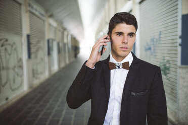 Young man on the phone wearing jacket and a wooden bow tie - RAEF000548