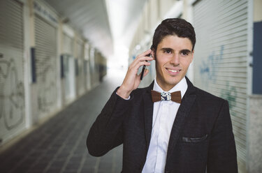 Young man on the phone wearing jacket and a wooden bow tie - RAEF000550