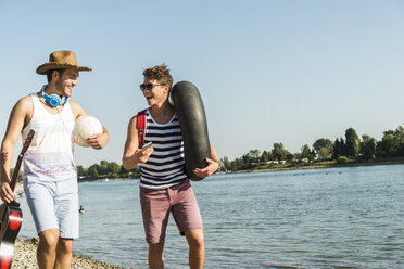 Two friends with inner tube and guitar walking at the riverside - UUF005845