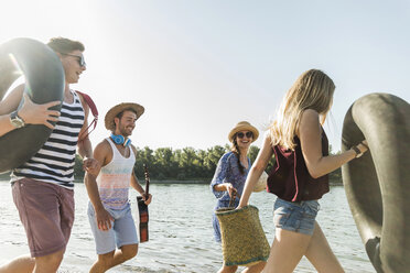 Freunde mit Schläuchen und Gitarre beim Spaziergang am Flussufer - UUF005848