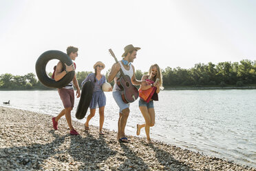 Friends with inner tubes and guitar walking at the riverside - UUF005849