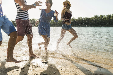 Happy friends running at the river - UUF005858