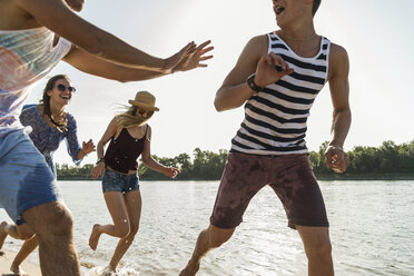 Glückliche Freunde beim Laufen am Fluss - UUF005860