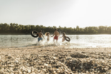 Friends with inner tubes running in river - UUF005874