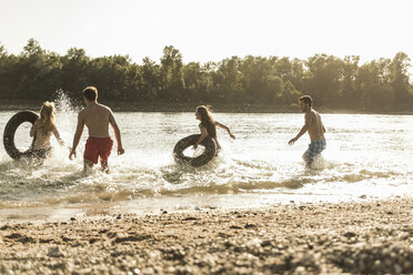 Playful friends with inner tubes in river - UUF005877