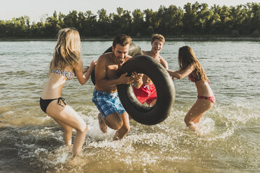 Playful friends with inner tubes in river - UUF005878