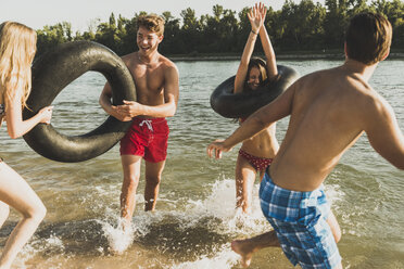 Playful friends with inner tubes in river - UUF005879