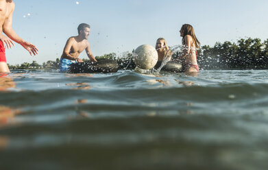 Glückliche Freunde mit Schläuchen und Ball im Wasser - UUF005883