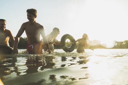 Glückliche Freunde mit Schläuchen und Ball im Wasser - UUF005884