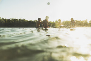 Happy friends with inner tubes and ball in water - UUF005885