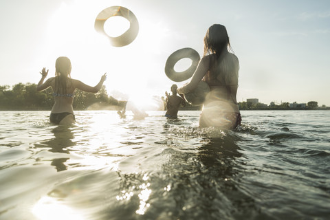 Happy friends throwing inner tubes in water stock photo