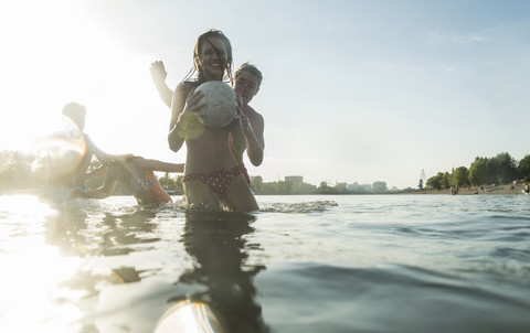 Zwei glückliche Paare mit Ball im Wasser, lizenzfreies Stockfoto