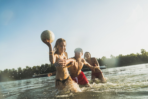 Happy friends with ball in water stock photo