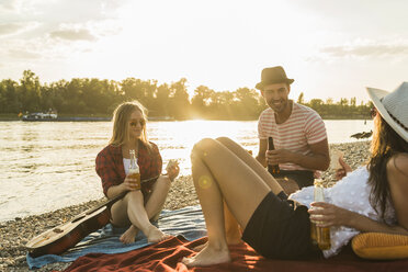 Friends relaxing at the riverside at sunset - UUF005902