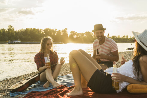 Freunde entspannen sich bei Sonnenuntergang am Flussufer - UUF005902