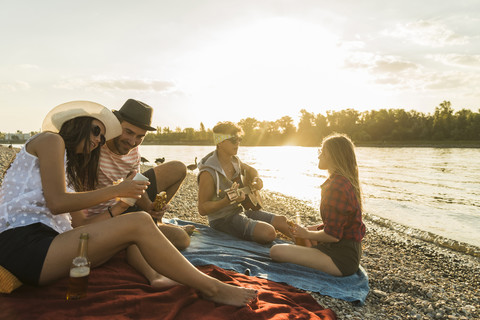 Friends relaxing at the riverside at sunset stock photo