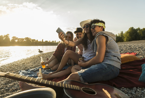 Friends taking a selfie at the riverside at sunset stock photo