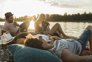 Friends relaxing at the riverside at sunset - UUF005909