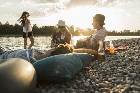 Freunde entspannen sich bei Sonnenuntergang am Flussufer - UUF005910