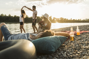 Friends relaxing at the riverside at sunset - UUF005911