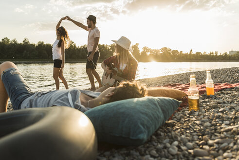 Freunde entspannen sich bei Sonnenuntergang am Flussufer - UUF005911