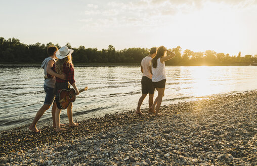 Two couples walking at the riverside at sunset - UUF005915