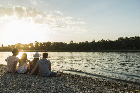 Freunde entspannen sich bei Sonnenuntergang am Flussufer - UUF005916