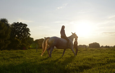 Junge Frau reitet auf Pferd, Freund führt - BFRF001558