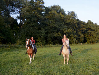 Zwei junge Frauen reiten auf ihren Pferden - BFRF001577