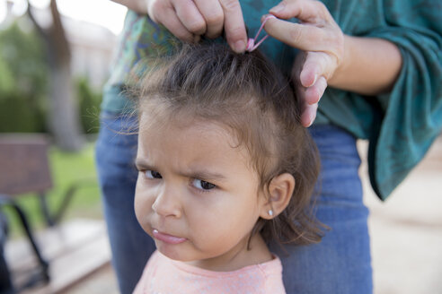 Mutter bindet die Haare ihrer kleinen Tochter zusammen, Nahaufnahme - ERLF000062