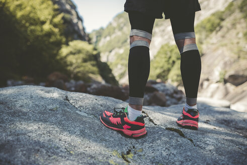 Ultra runner in mountains standing on rock - RAEF000558