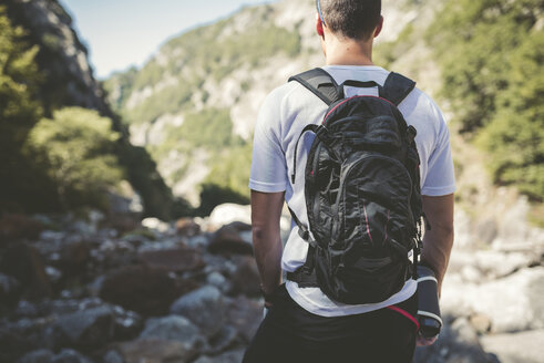 Ultra runner in mountains carrying backpack, looking at view - RAEF000559