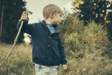 Kleiner Junge erkundet den Wald, geht mit seinem Stock im Gras - MFF002438