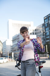 Germany, Berlin, young woman taking a picture with her smartphone - FKF001395