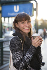 Deutschland, Berlin, Porträt einer glücklichen jungen Frau mit Kaffee zum Mitnehmen - FKF001399