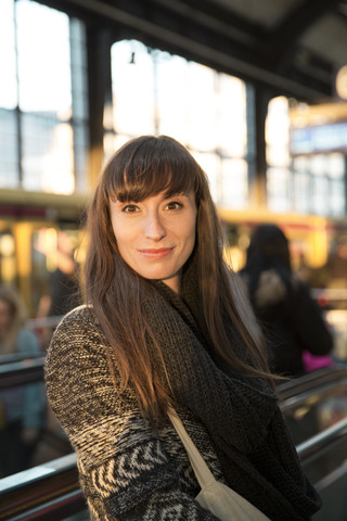 Deutschland, Berlin, Porträt einer lächelnden jungen Frau, die am Bahnsteig wartet, lizenzfreies Stockfoto