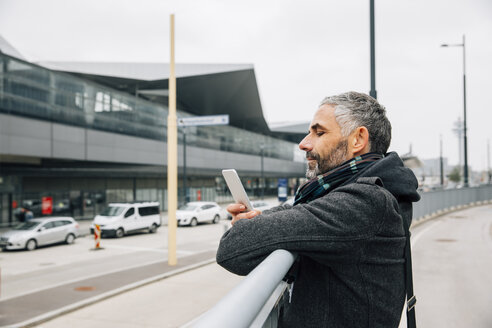 Österreich, Wien, Mann lehnt an einem Geländer in der Nähe des Hauptbahnhofs und schaut auf sein Smartphone - AIF000106
