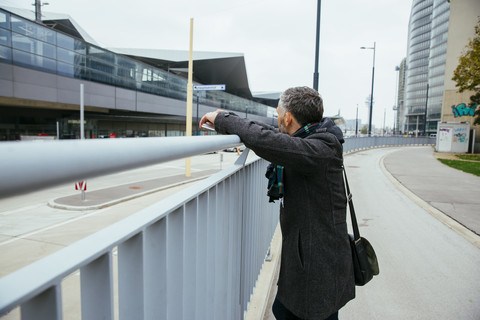 Österreich, Wien, Mann lehnt an einem Geländer und schaut auf den Hauptbahnhof, lizenzfreies Stockfoto