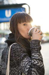 Deutschland, Berlin, junge Frau trinkt Kaffee zum Mitnehmen - FKF001406