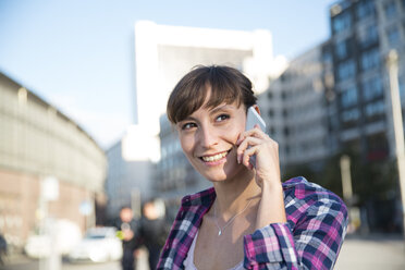 Deutschland, Berlin, Porträt einer jungen Frau, die mit einem Smartphone telefoniert - FKF001412