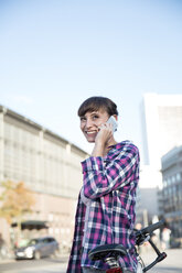 Deutschland, Berlin, Porträt einer jungen Frau, die mit einem Smartphone telefoniert - FKF001415