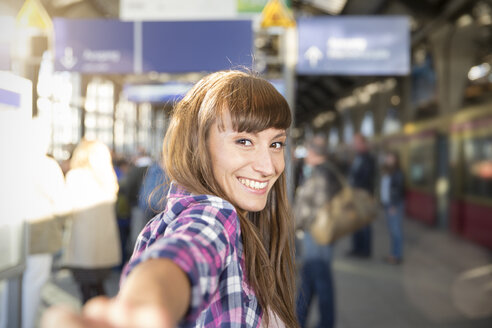 Deutschland, berlin, Porträt einer lächelnden jungen Frau, die sich am Bahnsteig an den Händen hält - FKF001424