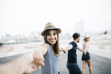 Spain, Barcelona, portrait of smiling young woman holding hands with her friends - JRFF000134